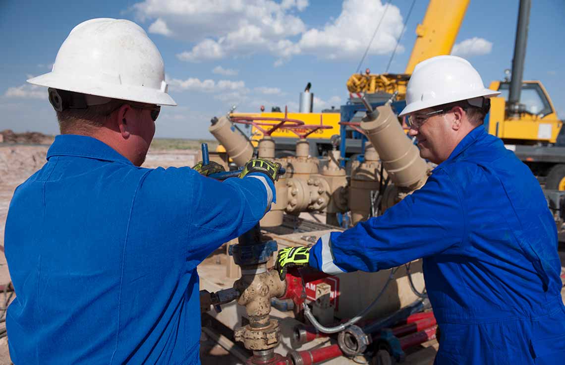 Photograph of Cameron personnel with wellsite frac and flowback equipment.
