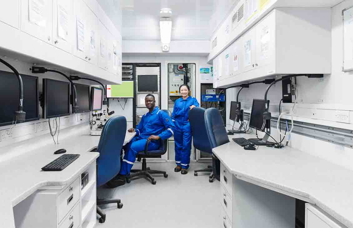 Photo of workers in blue coveralls in a mobile lab
