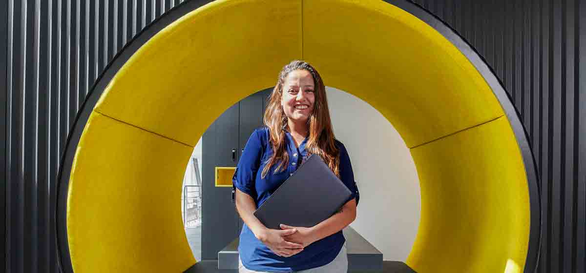 Woman standing in front of a yellow tunnel in an office building (Tier 1_Office_Clamart_OAT_0350)