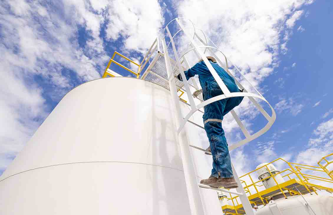 Photo of worker climbing up large tank