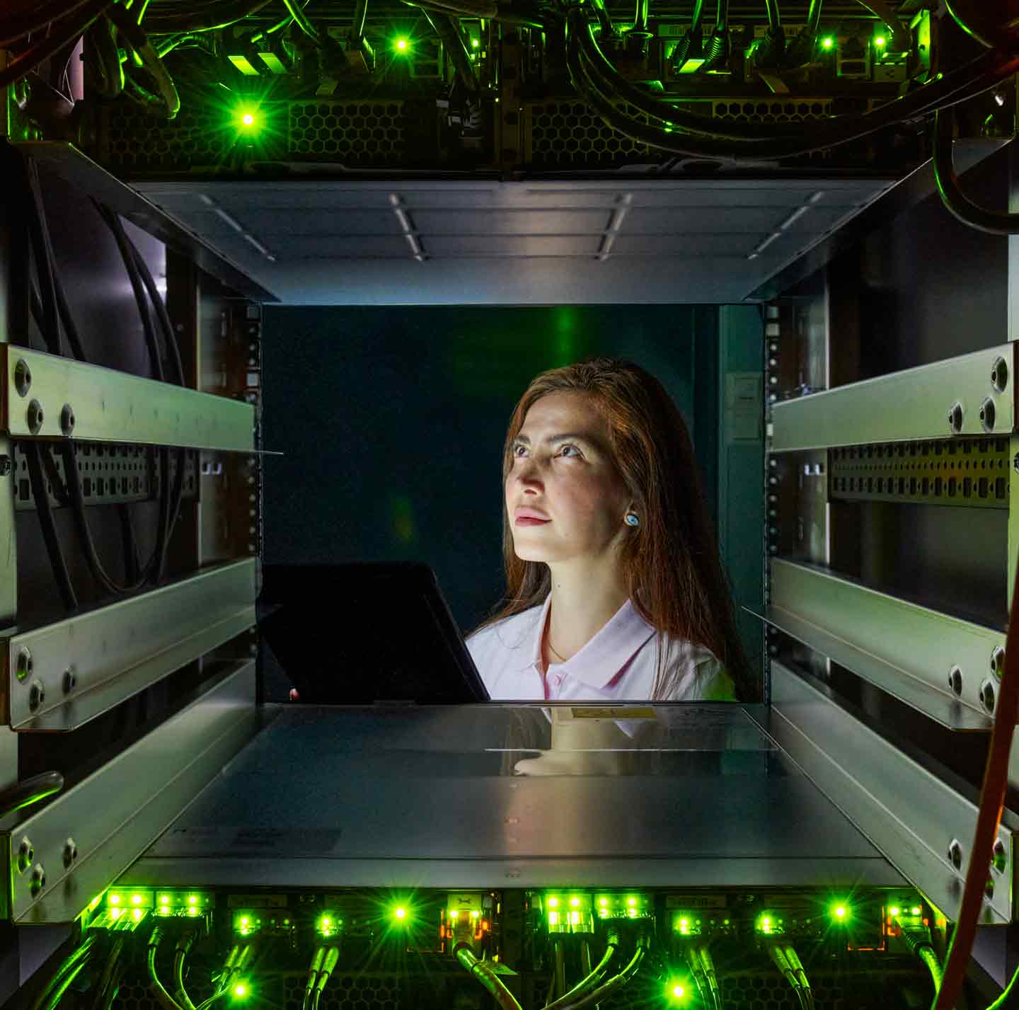 A female looking through a server box with circuit boards and wires