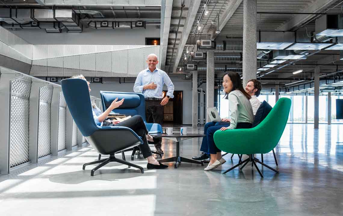 A group of employees sitting and talk with each other in an open-concept office building
