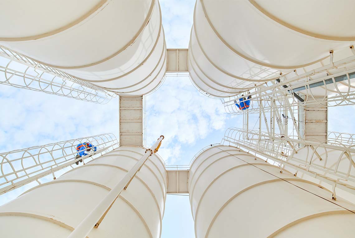 Lower view of people climbing the ladders on 2 white tanks (Tier 1_MaintenanceFacility_Oman_MENA_6864)