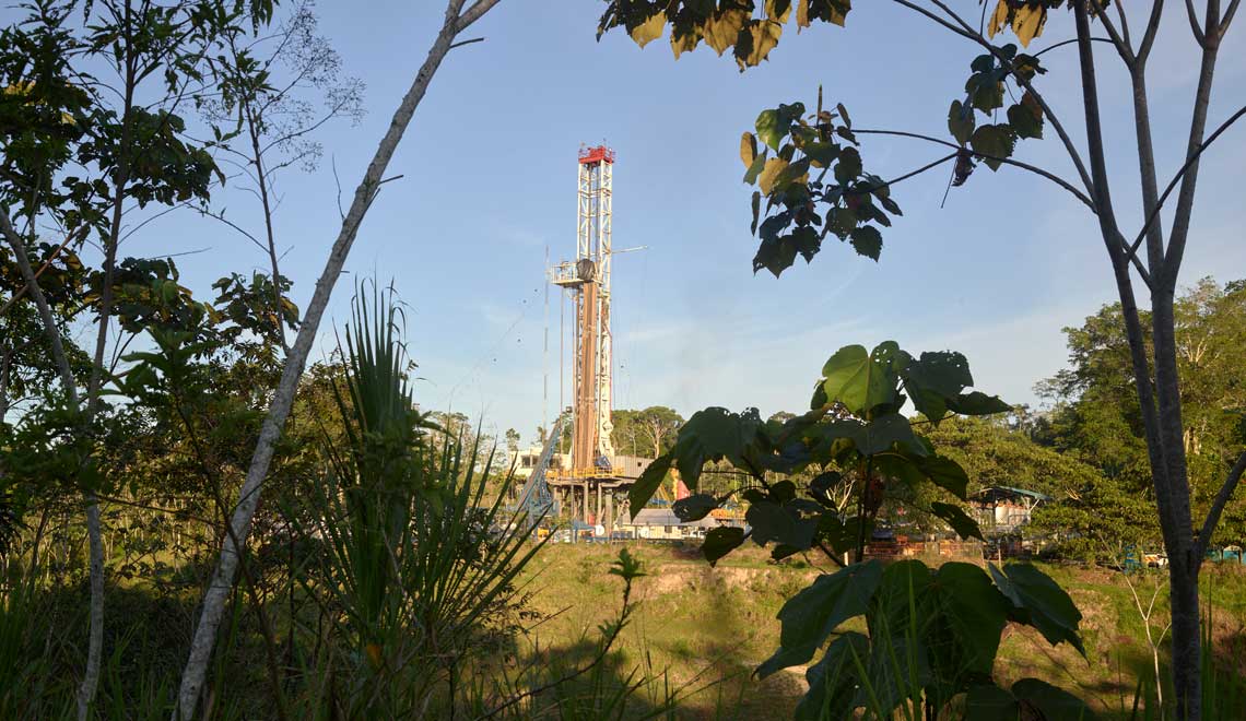 Drilling land rig surrounded by trees and greenery