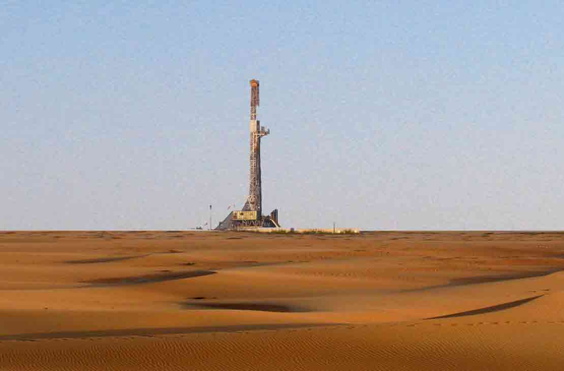 A land rig in the distance, across a sandy landscape