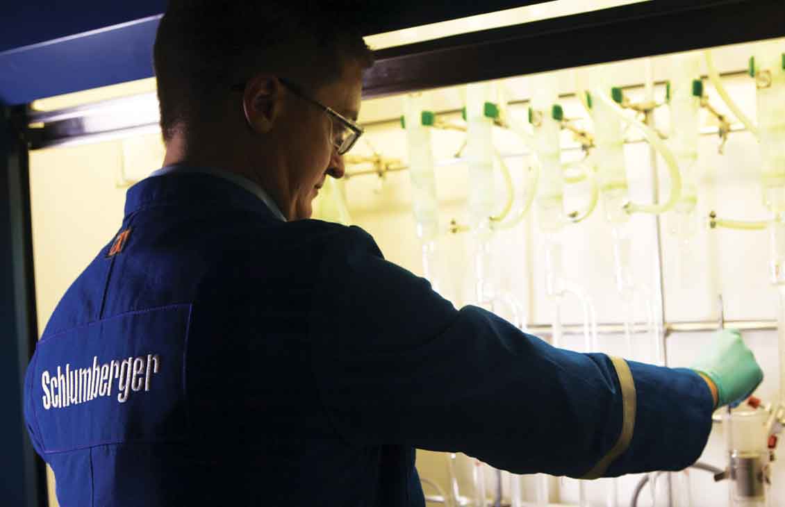 Schlumberger worker performing analysis and tests in a reservoir lab.