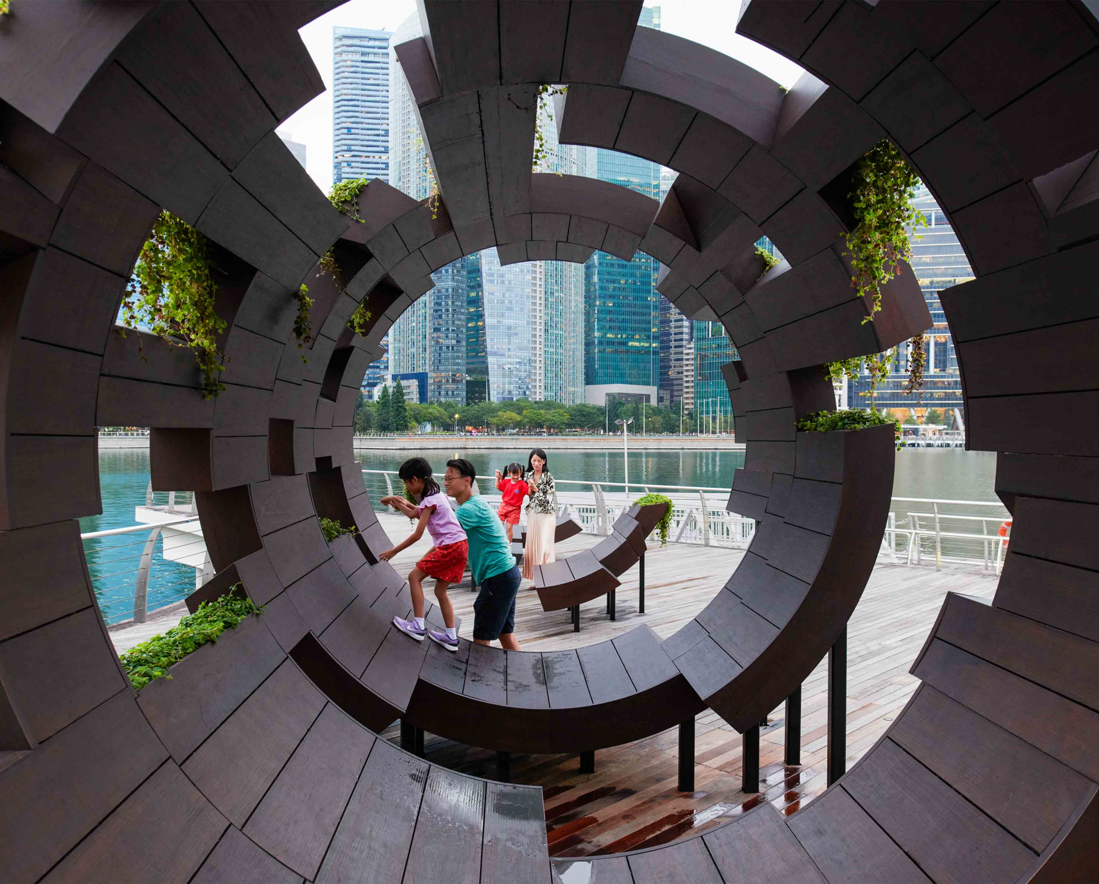 a family and children playing outside on a tubular architectural piece